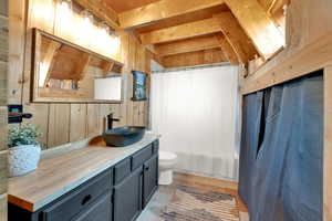 Full bathroom featuring vanity, wooden walls, shower / bath combo with shower curtain, and tile patterned flooring