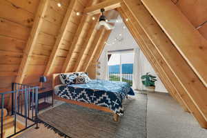 Carpeted bedroom featuring access to exterior, lofted ceiling, and wood walls