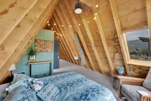Carpeted bedroom with wood walls and vaulted ceiling