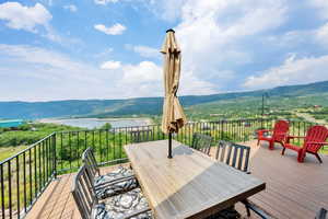 Wooden terrace featuring a water and mountain view and outdoor dining space