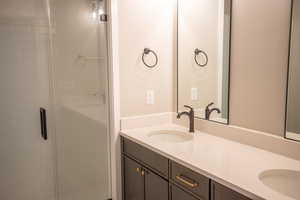 Bathroom featuring double vanity and a stall shower