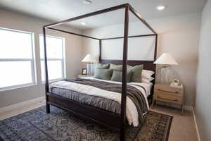 Bedroom featuring light carpet, a textured ceiling, and recessed lighting