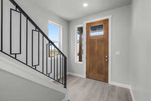 Foyer entrance with light wood-style flooring, stairway, and recessed lighting