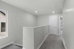 Hallway with an upstairs landing, carpet, and recessed lighting