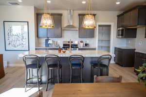Kitchen with decorative backsplash, wall chimney exhaust hood, stainless steel appliances, light stone countertops, and a breakfast bar area