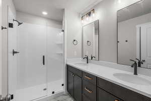 Bathroom featuring double vanity, a textured ceiling, light marble finish flooring, and a stall shower