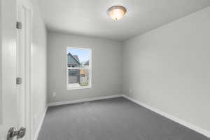 Carpeted spare room with baseboards and a textured ceiling