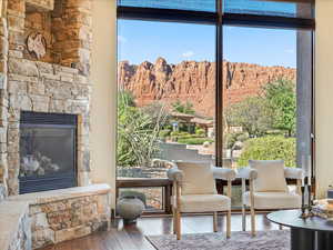 Sitting room with wood finished floors, a stone fireplace, and healthy amount of natural light
