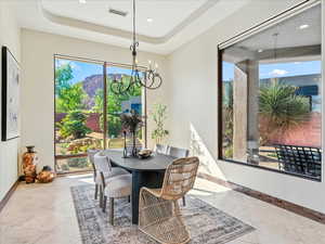 Dining room with a chandelier, healthy amount of natural light, a raised ceiling, and recessed lighting