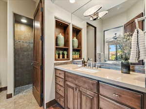 Full bathroom with vanity, tiled shower, and tile patterned flooring