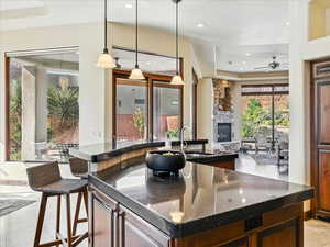 Bar area with a tray ceiling, recessed lighting, decorative light fixtures, a fireplace, and ceiling fan
