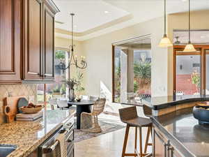 Kitchen with dark stone counters, pendant lighting, backsplash, recessed lighting, and a chandelier