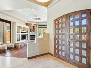 Tiled foyer with recessed lighting, ceiling fan, a raised ceiling, and a stone fireplace