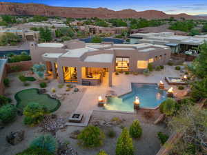 Rear view of house with stucco siding, a hot tub, a mountain view, a fenced backyard, and an outdoor fire pit