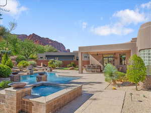 View of swimming pool with a patio, outdoor dining space, a ceiling fan, a mountain view, and a pool with connected hot tub