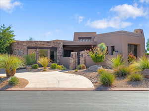 Pueblo revival-style home with stucco siding and stone siding
