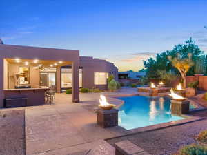 Pool at dusk with a fire pit, a jacuzzi, a patio, and a ceiling fan