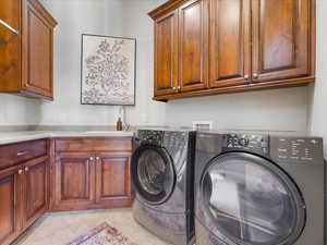 Washroom with cabinet space, washing machine and dryer, and light tile patterned flooring