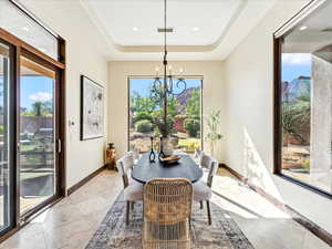 Dining room with healthy amount of natural light, a raised ceiling, a chandelier, and recessed lighting