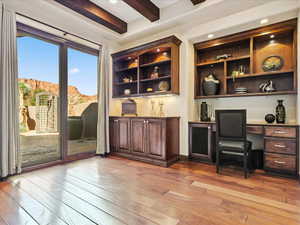 Home office with built in study area, beamed ceiling, light wood-style flooring, and recessed lighting