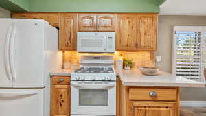 Kitchen with backsplash, gas stove, and under cabinet lighting