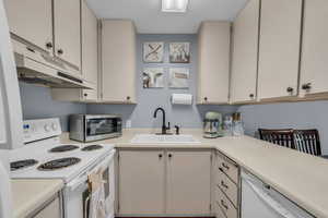 Kitchen with white appliances, light countertops, and under cabinet range hood