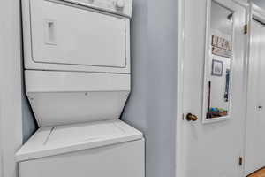 Laundry area featuring stacked washer / drying machine and a textured wall