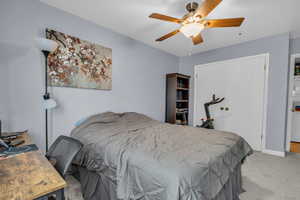 Bedroom with carpet floors, a desk, and a ceiling fan