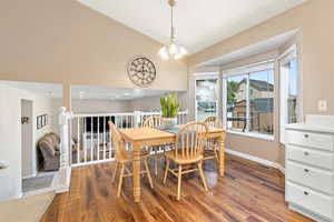 Dining area featuring vaulted ceiling, wood finished floors, and a chandelier