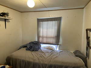 Bedroom featuring a textured ceiling and crown molding