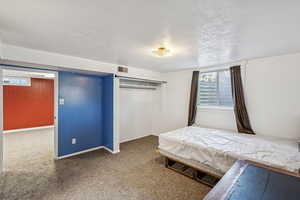 Carpeted bedroom featuring a textured ceiling and a closet