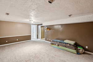 Finished below grade area with carpet flooring and a textured ceiling