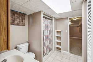 Bathroom featuring a paneled ceiling, a shower stall, and tile patterned flooring