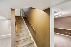 Stairway with carpet floors and a textured ceiling
