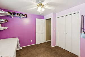Carpeted bedroom featuring a ceiling fan and a closet