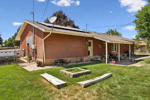 Back of property with roof mounted solar panels, brick siding, a patio area, and a gate