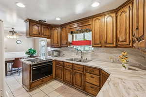 Kitchen with decorative backsplash, brown cabinets, range with electric cooktop, a peninsula, and a ceiling fan