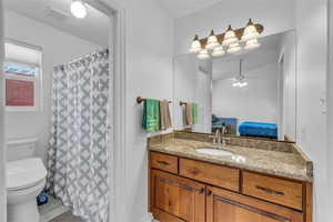 Ensuite bathroom with vanity, curtained shower, and ceiling fan