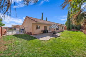 Back of house with stucco siding, a tiled roof, a patio area, and a gate