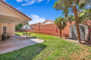 Fenced backyard featuring a storage shed and a patio