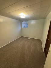 Carpeted spare room featuring a paneled ceiling