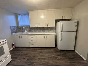 Kitchen featuring white cabinets, white appliances, light countertops, and dark wood-style flooring