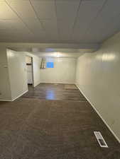 Empty room featuring dark wood-style floors and a drop ceiling