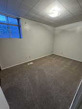 Carpeted spare room featuring a paneled ceiling