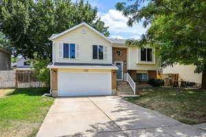 Split foyer home with concrete driveway, brick siding, and an attached garage