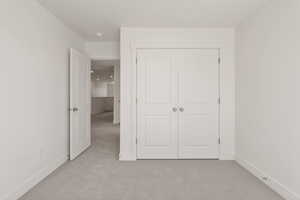Unfurnished bedroom with light colored carpet and a closet