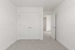 Unfurnished bedroom with light colored carpet and a closet