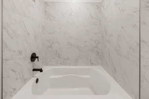 Full bath featuring a combined bath / shower with marble appearance