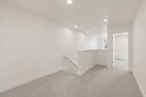 Empty room with light colored carpet and recessed lighting