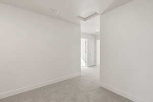 Empty room featuring attic access and carpet flooring